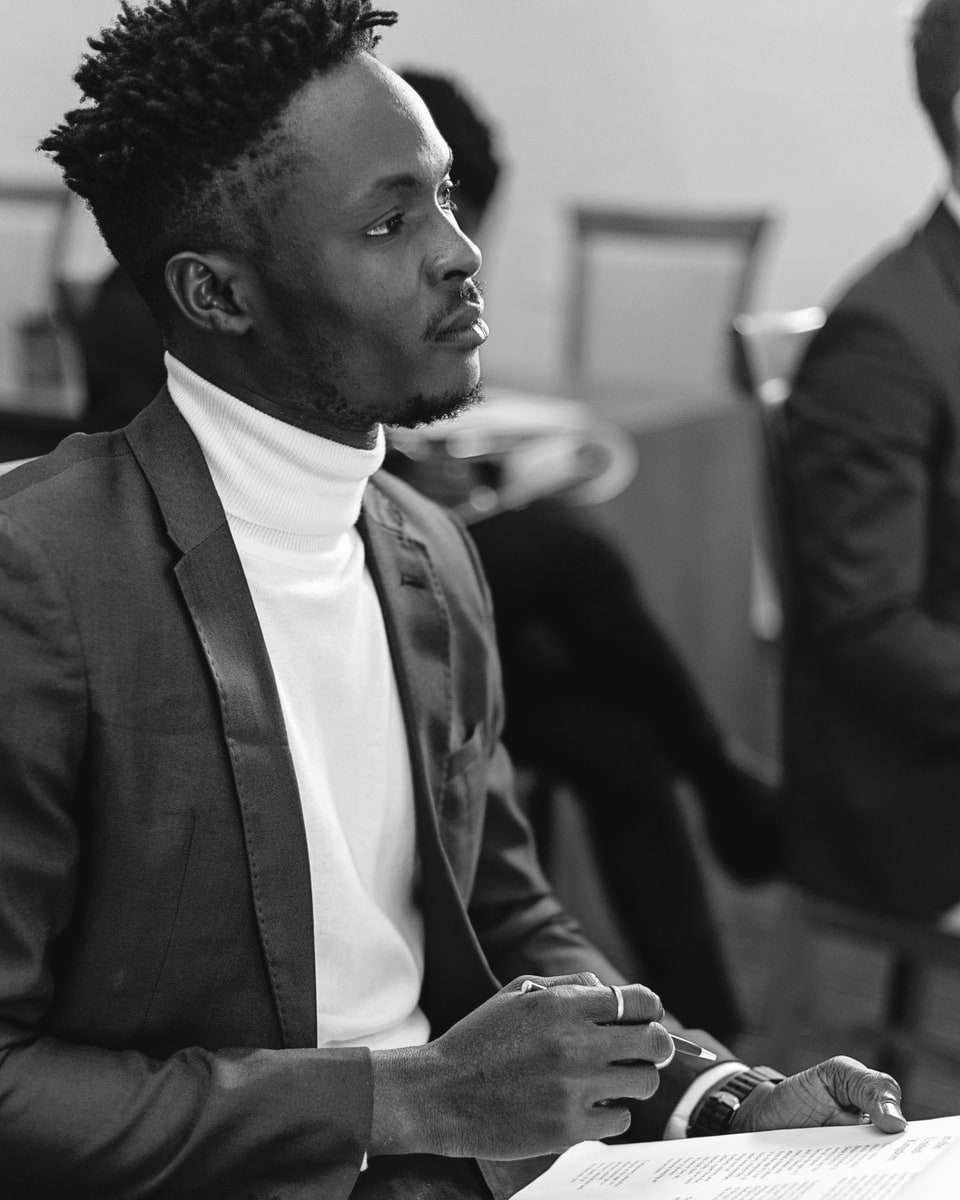 A man in a suit listening closely, with a printed briefing in his hands.
